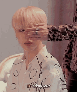 a person is covering a boy 's eye with their hand and says `` d okay , cut '' .