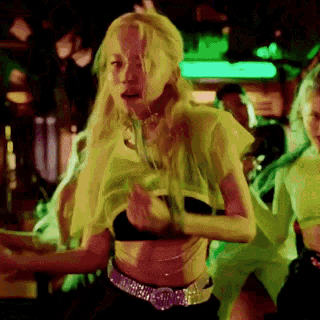 a woman in a green top and black bra is dancing