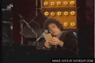 a man is reading a piece of paper in front of a microphone with the words make gifs at gifsoup.com at the top