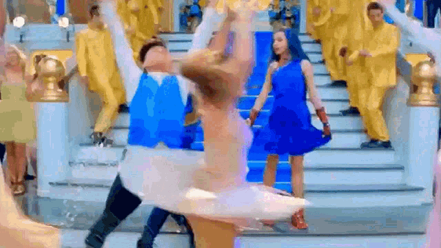 a group of people are dancing on a stage while a ballerina is dancing .
