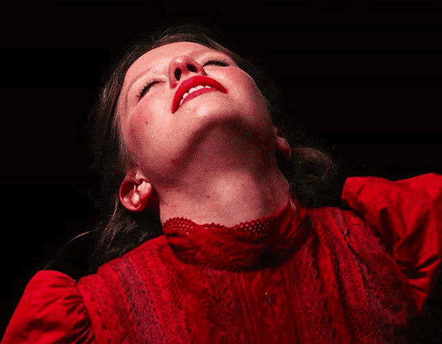 a woman in a red dress looks up with her mouth open
