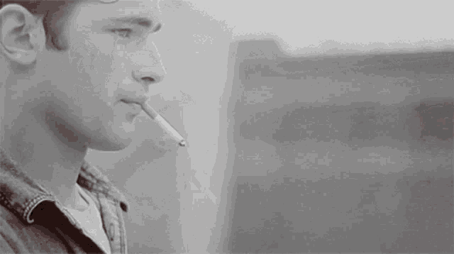 a man is smoking a cigarette in a black and white image