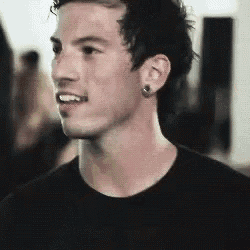 a close up of a young man wearing a black shirt and earring .