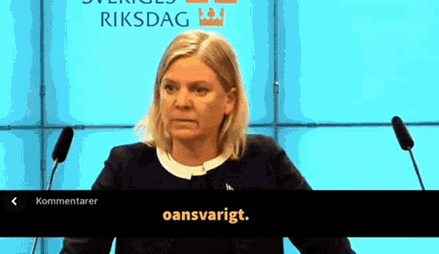 a woman is giving a speech in front of a sign that says riksdag