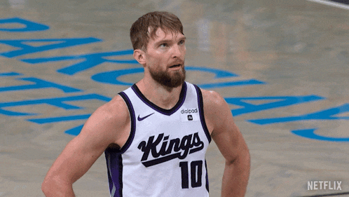 a man wearing a kings jersey stands on a court