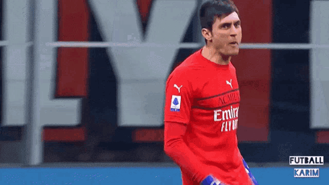 a soccer player wearing a red emirates jersey