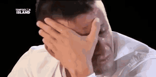 a man is covering his face with his hand while crying .