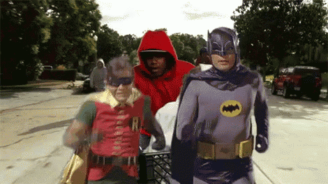 a group of people dressed as batman and robin walking down a street