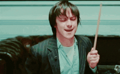 a man in a suit is holding a wooden stick and smiling