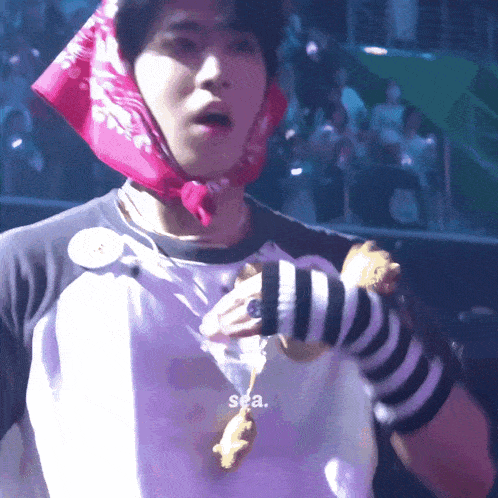 a man wearing a bandana and striped sleeves holds a stuffed animal