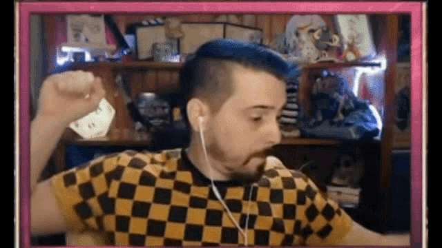 a man with blue hair is wearing ear buds and a yellow and black checkered shirt .