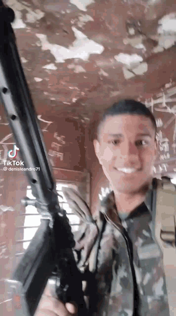 a man in a military uniform is holding a rifle and smiling .