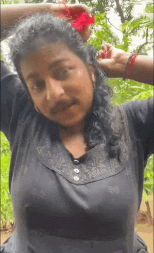 a woman is holding a red flower in her hair .