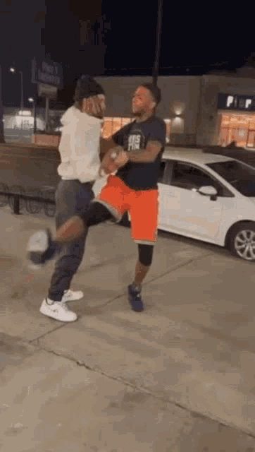 two men are standing next to each other on a sidewalk .
