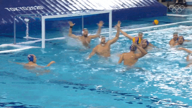 a group of men are playing water polo in a pool with a tokyo 2020 banner in the background
