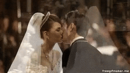 a bride and groom are kissing in front of a crowd of people .