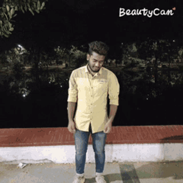 a man wearing a yellow shirt and jeans is standing in front of a beautycam watermark