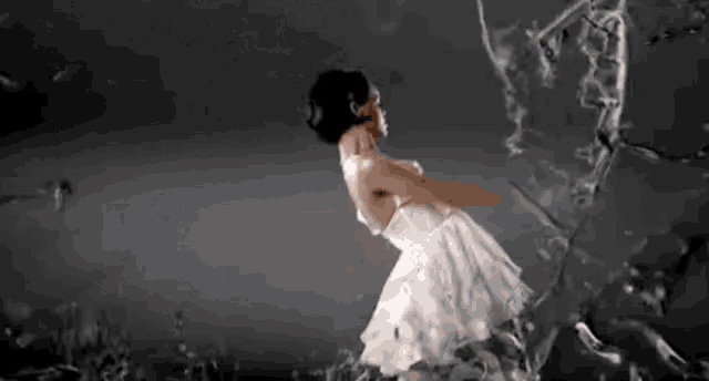 a woman in a white dress is standing in front of a broken glass .