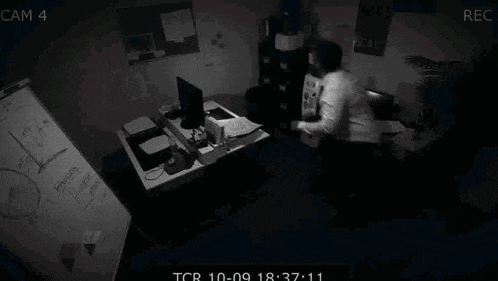 a man is sitting at a desk in front of a computer in a dark office .