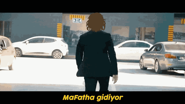 a man in a suit is walking in a parking lot with the words mafatha gidiyor written below him