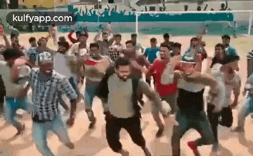 a large group of people are dancing on a field .
