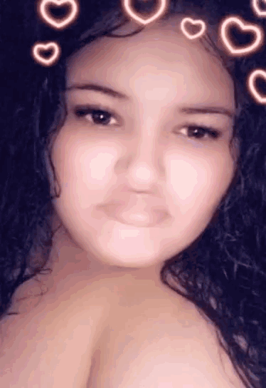 a woman with long curly hair is taking a selfie with hearts around her head .