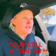 a woman wearing a hat is sitting in a car with the words your still a traitor