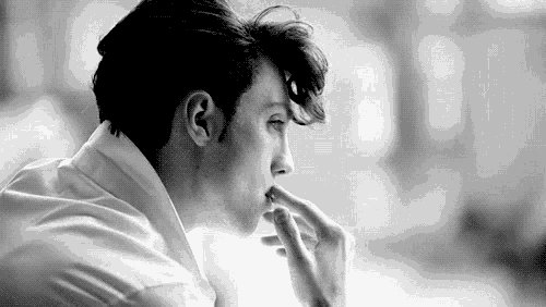a man in a white shirt is smoking a cigarette .