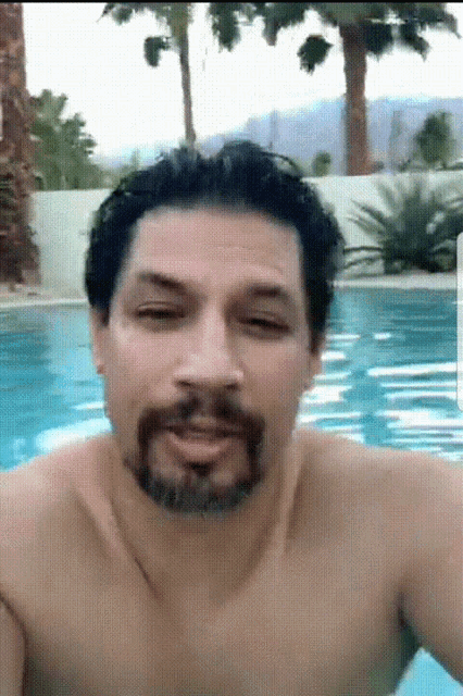 a shirtless man with a beard is swimming in a swimming pool