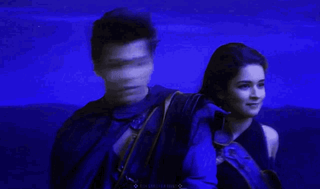 a man and a woman are standing next to each other in a dark blue background .