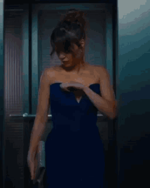 a woman in a blue strapless dress is standing in an elevator .