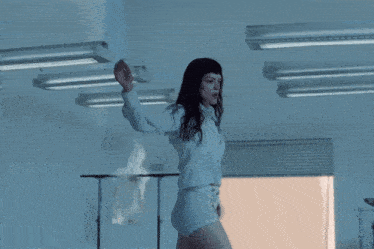 a woman in a white shirt and shorts is walking in a room