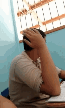 a man sitting at a desk with his hands on his head