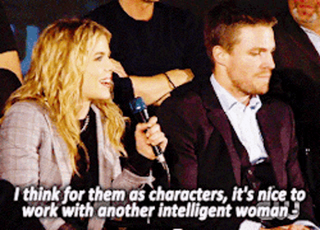 a man and a woman are sitting next to each other with the woman holding a microphone
