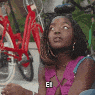 a woman in a purple top is sitting in front of a row of bicycles and says ei !