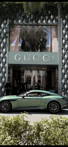 a green sports car is parked in front of a store called gucci