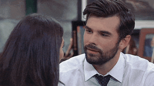 a man with a beard and tie is looking at a woman