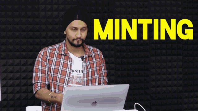 a man in a plaid shirt is working on a laptop with the words minting behind him