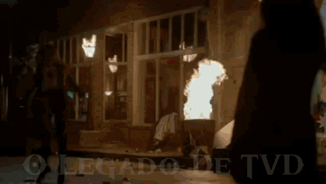 a woman is standing in front of a fire with the words o legado de t on the bottom .