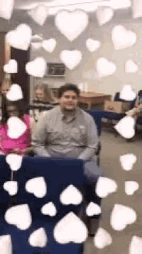 a man is sitting in a chair with hearts coming out of the window