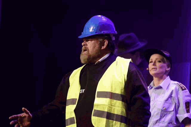 a man wearing a blue hard hat and a yellow vest that says gt on it