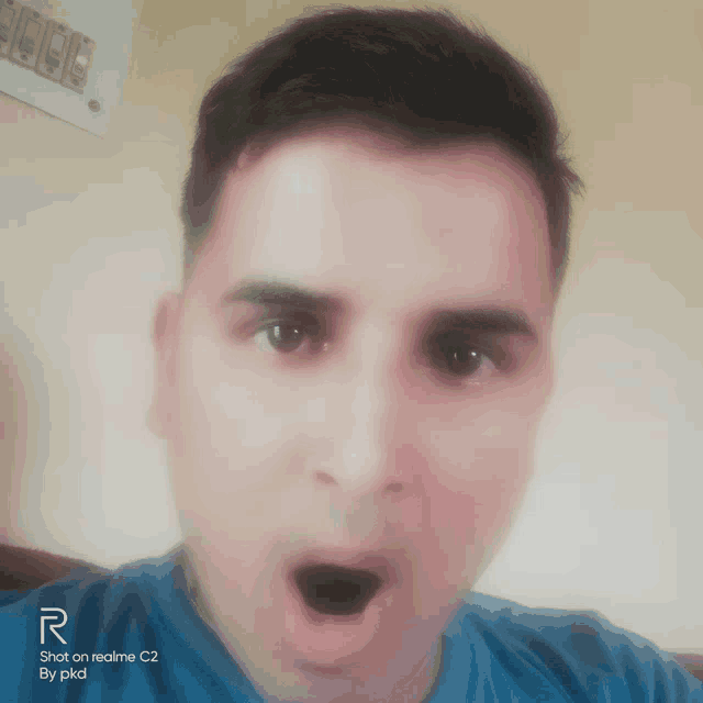 a man with a surprised look on his face has a shot on realme c2 by pkd on the bottom right
