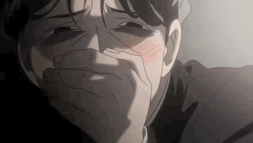 a close up of a man covering his mouth with his hand in a dark room .