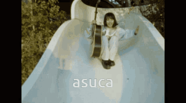 a girl with a guitar on a slide with the word asuca on the bottom