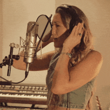 a woman is singing into a microphone with headphones on