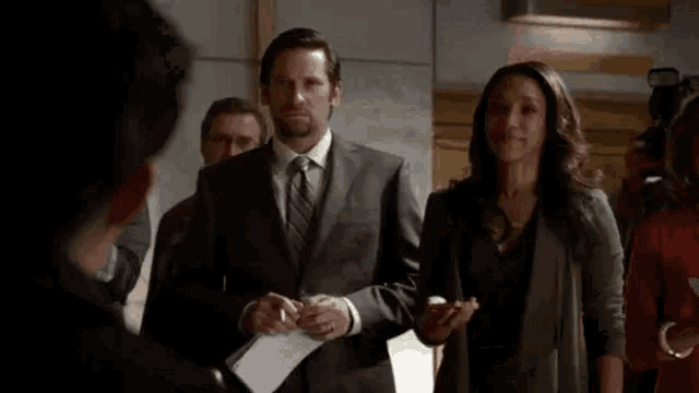 a man and a woman are standing next to each other in a room with a group of people .