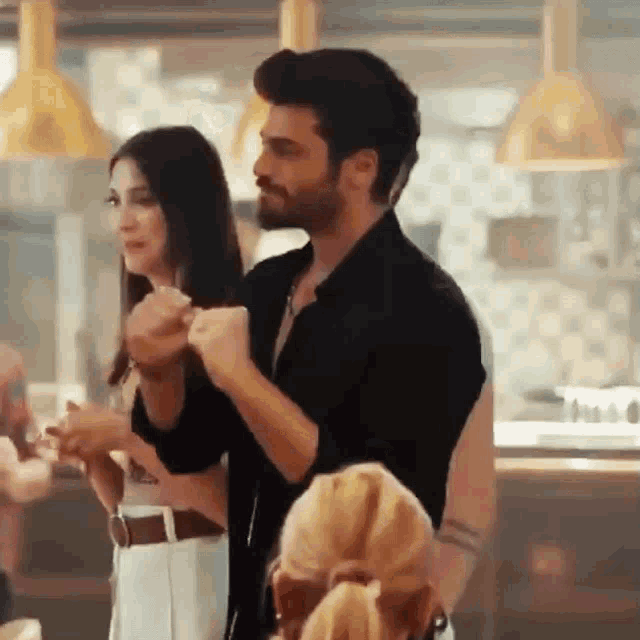 a man and a woman are standing next to each other in a restaurant holding hands .