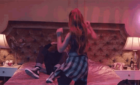 a man and a woman are dancing on a bed in a bedroom .