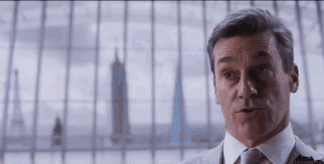 a man in a suit and tie is looking out of a window .