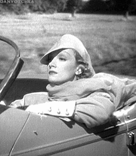 a woman is sitting in the back seat of a car wearing a hat and scarf .
